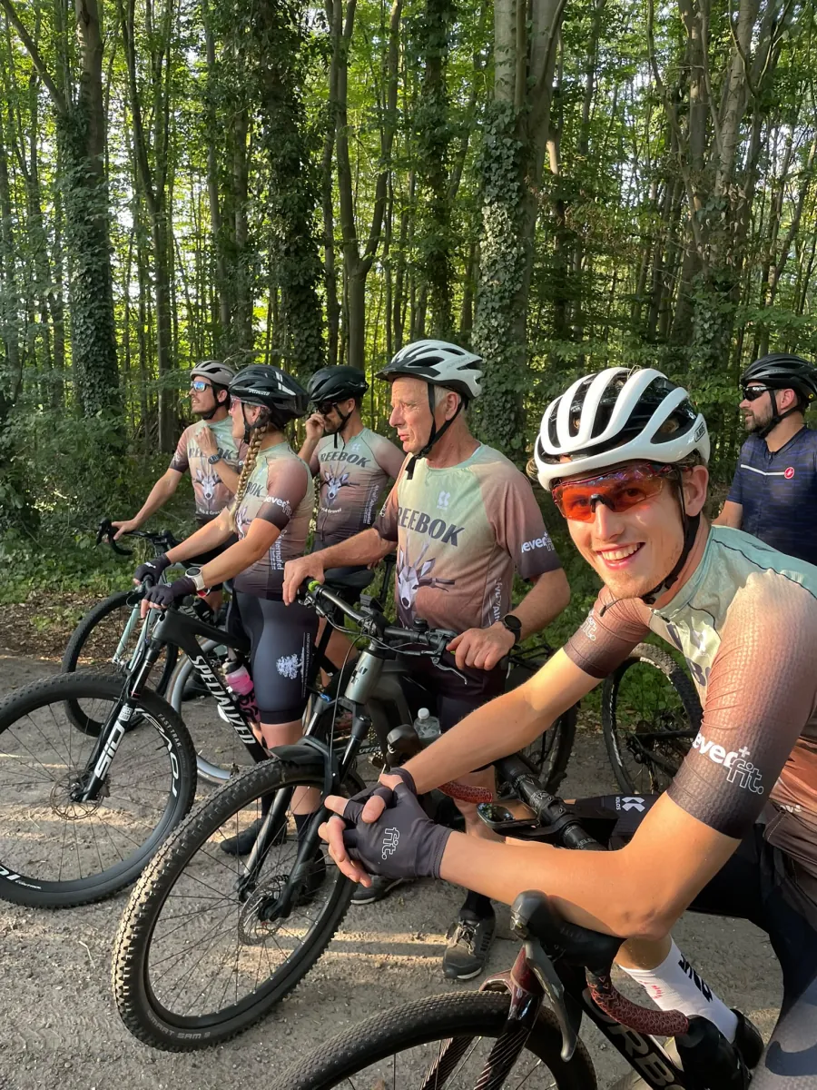 Clubleden zitten op hun fietsen tijdens een pauze in het bos.